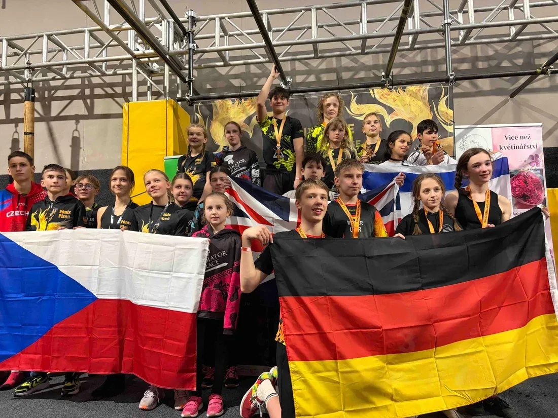 Vyhlášení výsledků Fénix Challenge – mladí závodníci s vlajkami České republiky, Německa a Velké Británie